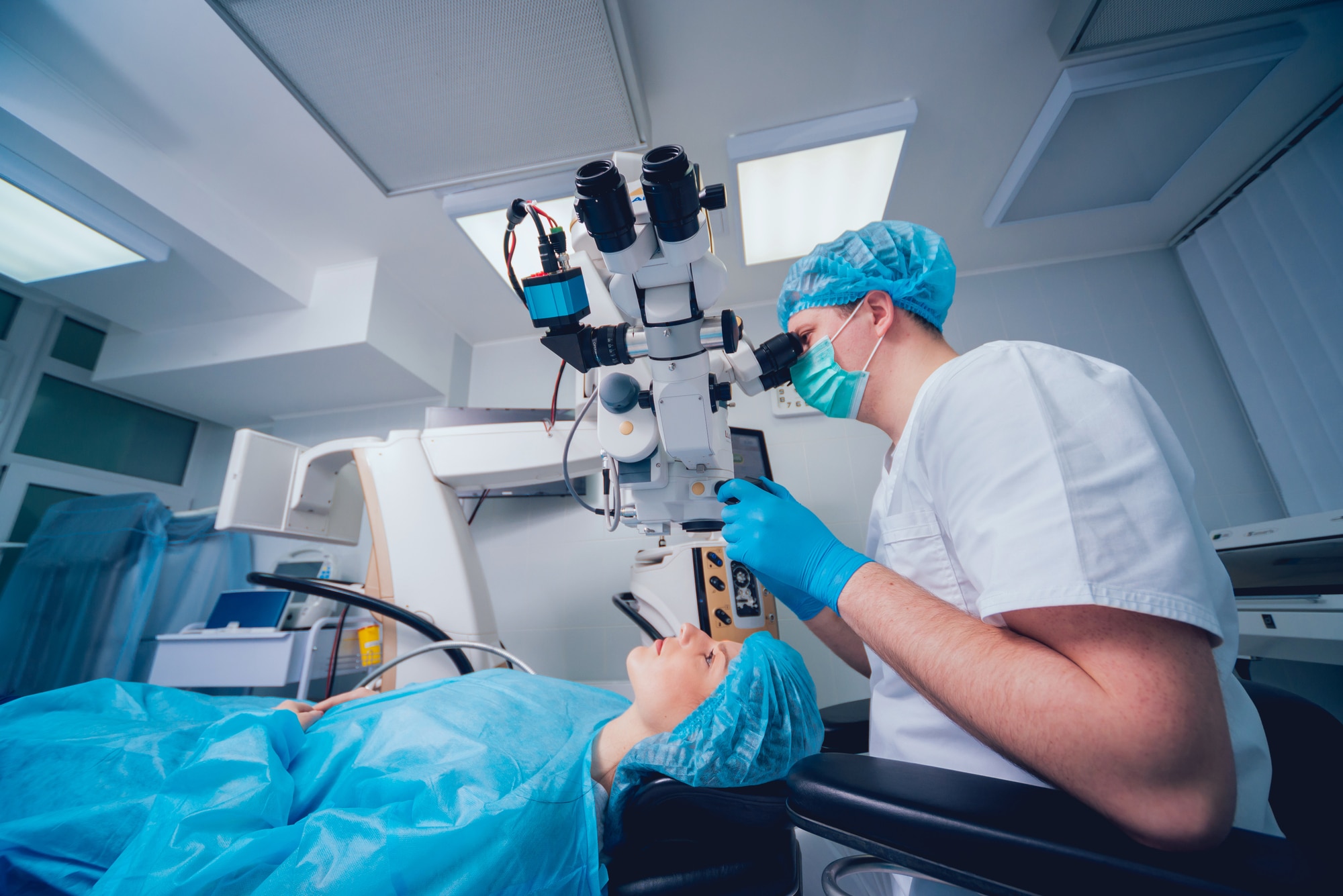 A surgeon operating at an ophthalmic surgical microscope in a sterile operating room